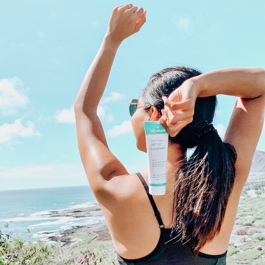 Woman using MDacne oil-free sunscreen to prevent breakouts