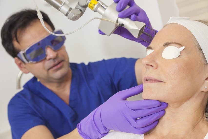 Dermatologist conducting ablative laser resurfacing on woman with acne scars