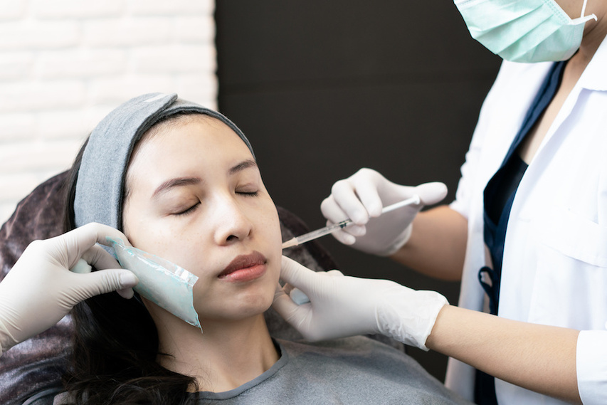Dermatologist administering dermal filler to woman with depressed acne scars
