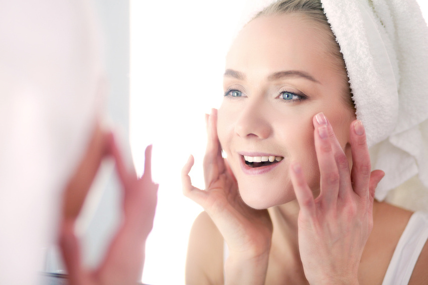 Woman with normal skin examining face in mirror