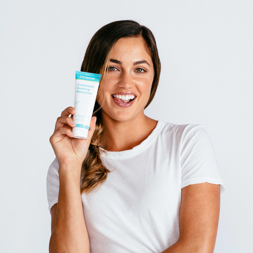 Woman using MDacne soothing moisturizer for acne-prone skin