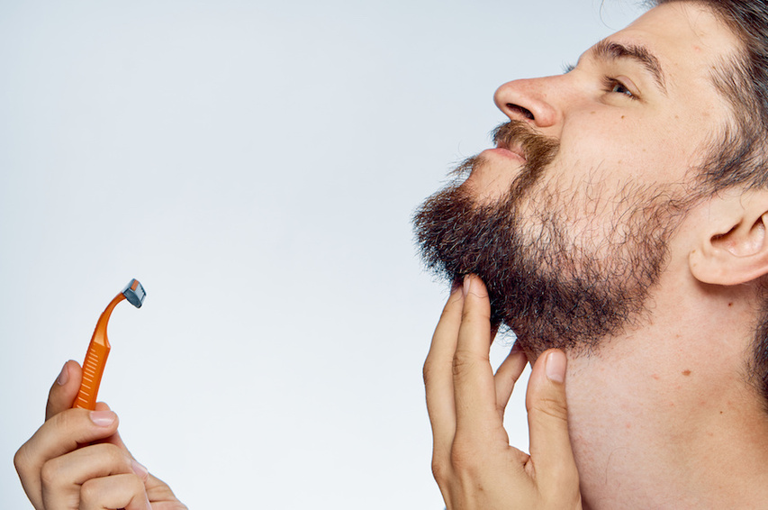 Man holidng shaving razor to face